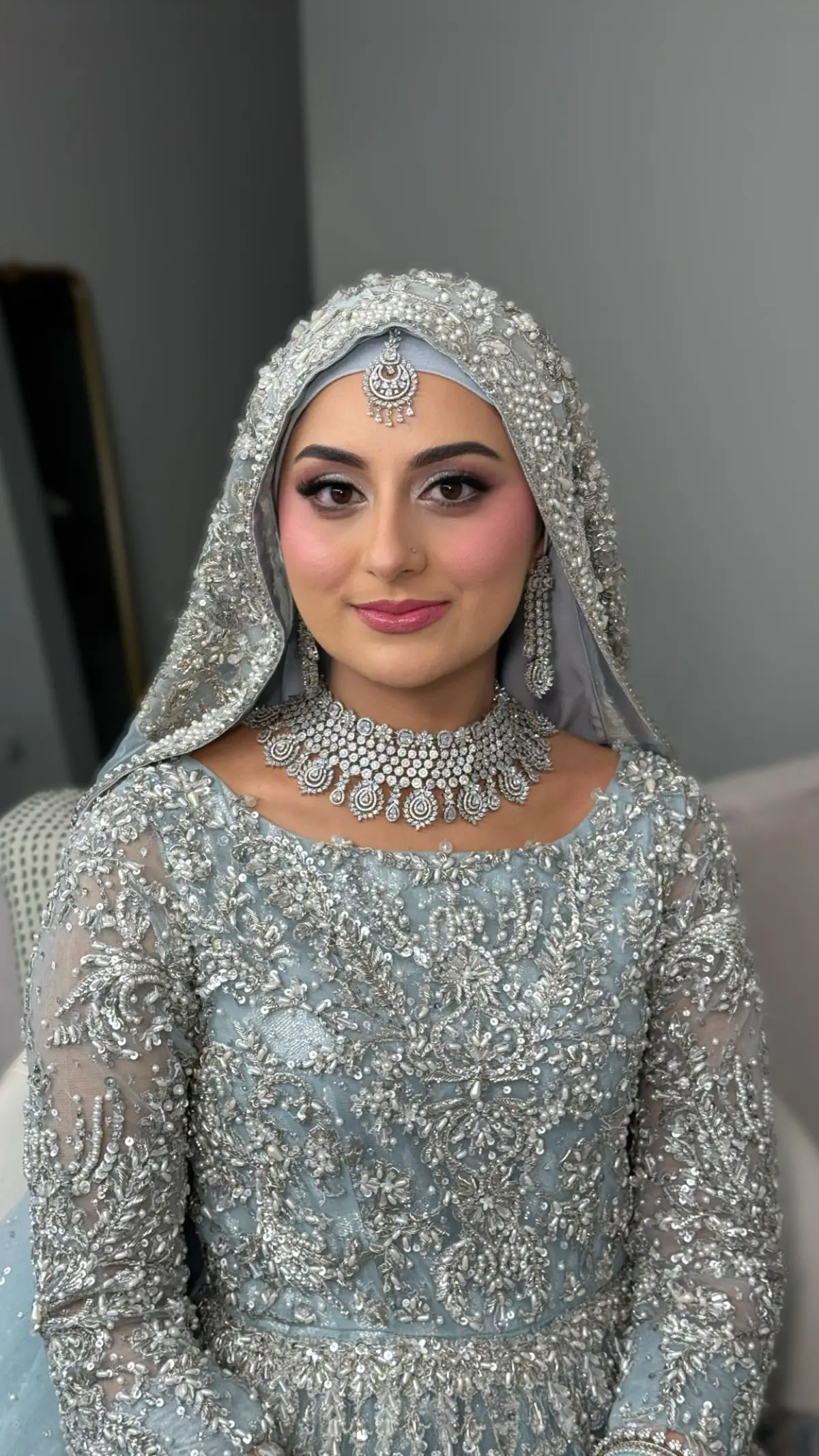 Bride in powder blue with a voluminous hijab and a silver diamond set.