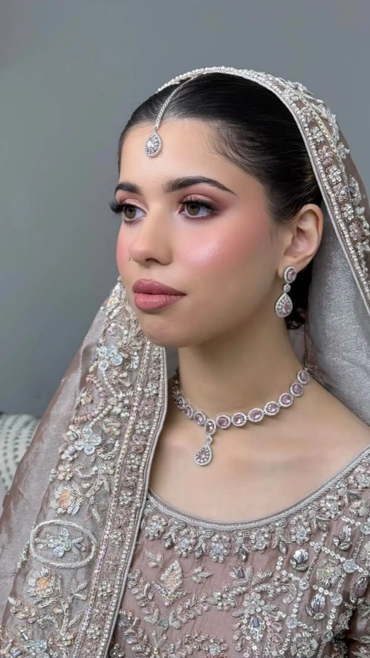 Bride in champagne and ivory with a pearl and diamond set, soft veil and a sleek centre part.
