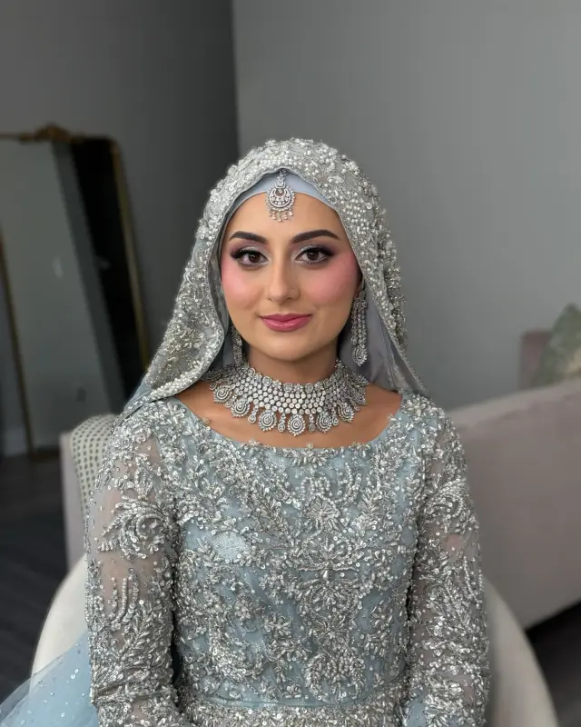 Bride in powder blue with a voluminous hijab and a silver diamond set.